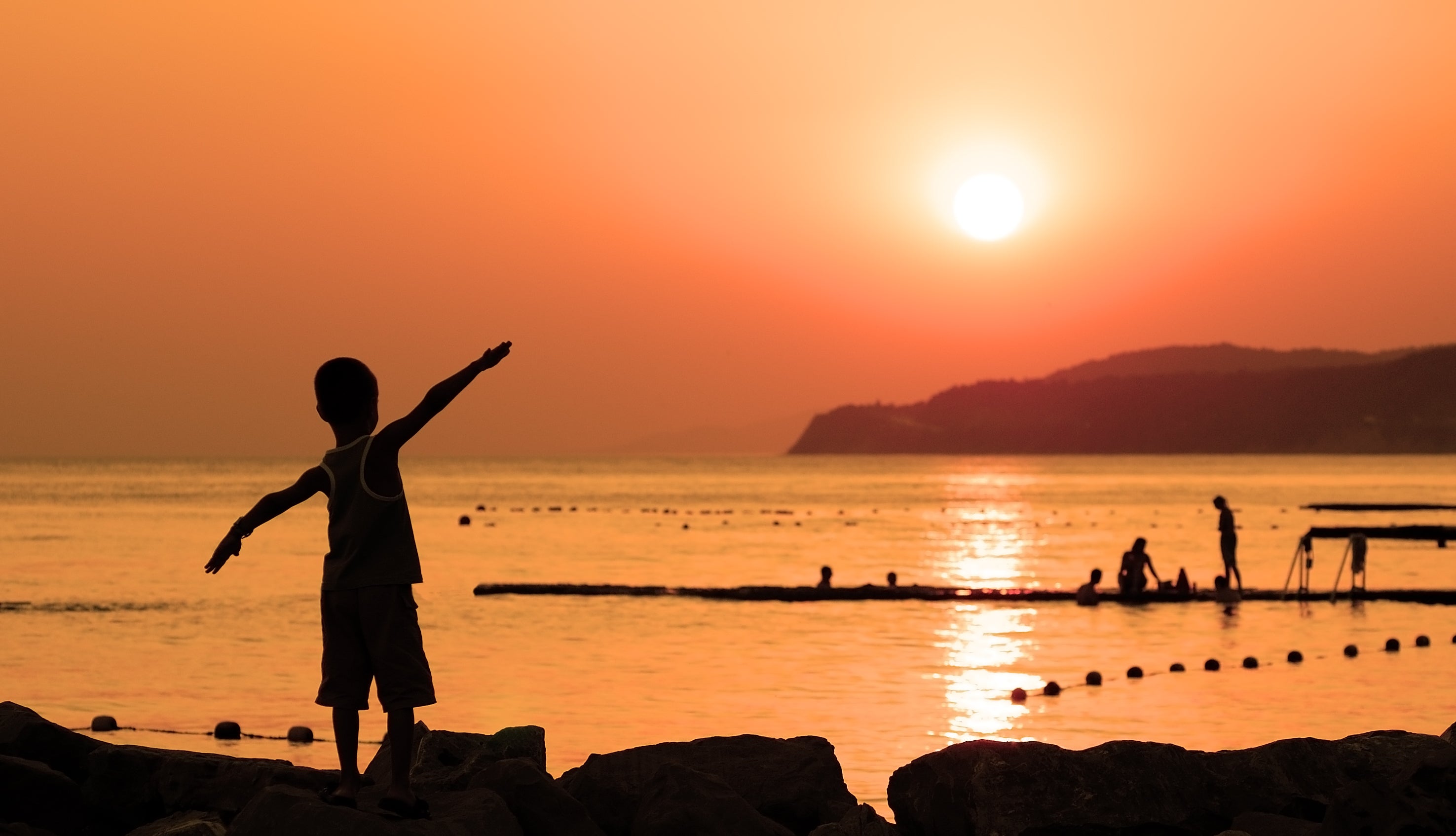 silhouette-of-child-against-orange-sunset-at-sea-w-2021-08-26-15-35-22-utc.jpg